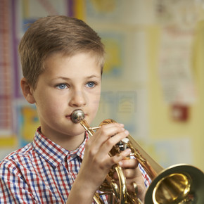 学习在学校音乐课上吹小号的男孩