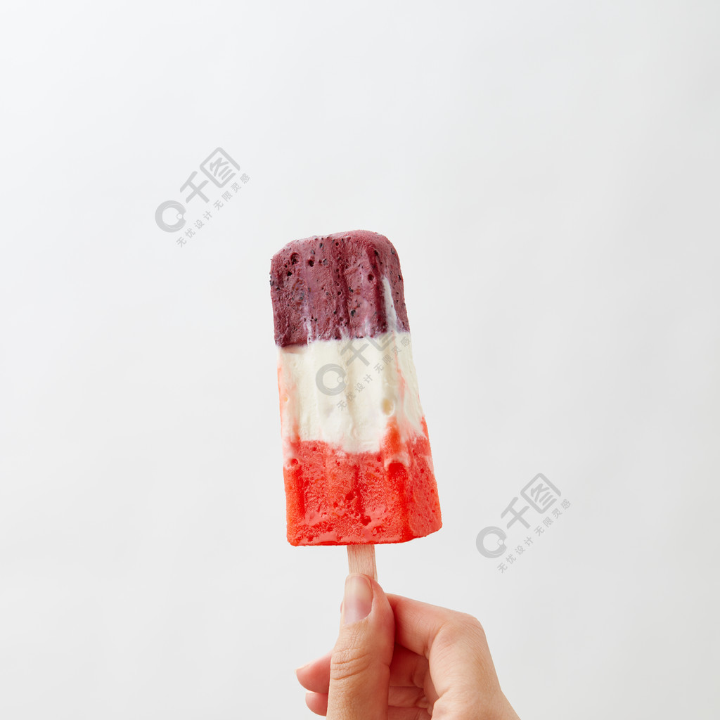 woman&rsquo s手拿着在白色背景的一个色的莓果冰淇凌冰棍与拷贝空间