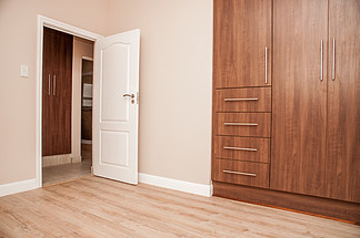 新房卧室，内置橱柜和层<i>压</i>地板，朝着敞开的门看