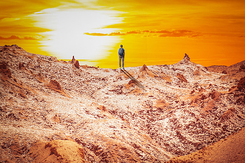 一个人在阿塔卡马沙漠的安第斯山脉的岩石间行走
