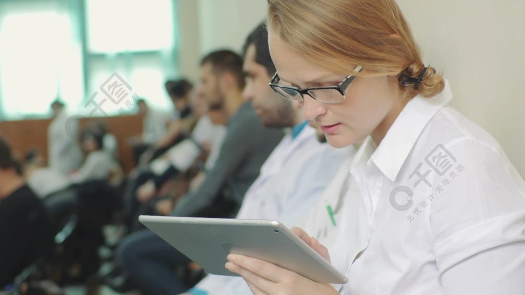 年轻的女医生或学生使用平板电脑在医学会议，座谈会或演讲期间做笔记