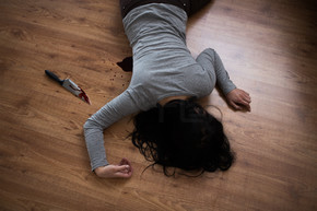 谋杀，谋杀和人们观念-死者的尸体和刀子躺在犯罪现场的地板上的血液（舞台照片）在犯罪现场的地板上躺着的死女人尸体