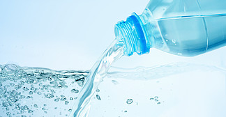 饮用，健康饮食和食物存储的概念— —关闭从塑料瓶倒在蓝色背景的饮用水