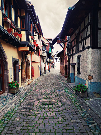 老Eguisheim村庄的狭窄的街道有半木料半灰<i>泥</i>的中世纪房子的沿著名酒路线在阿尔萨斯，法国