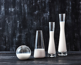 与乳制品的玻璃挤奶站立在黑背景的一张黑木桌上与拷贝空间天然有机乳制品天然有机乳制品牛奶<i>保</i>存技术在一个黑色的木桌上的玻璃瓶不同形状