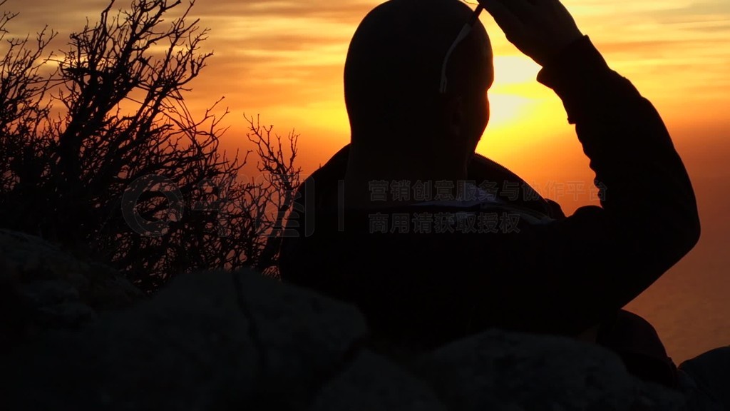 ein Mann beobachtet ein gleiend gelben SonnenuntergangBlickrichtung ist in Sonneso dass der Mann n