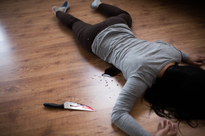 谋杀，谋杀和人们观念-死者的尸体和刀子躺在犯罪现场的地板上的血液（舞台照片）在犯罪现场的地板上躺着的死女人尸体在犯罪现场的地板上躺着的死女人尸体