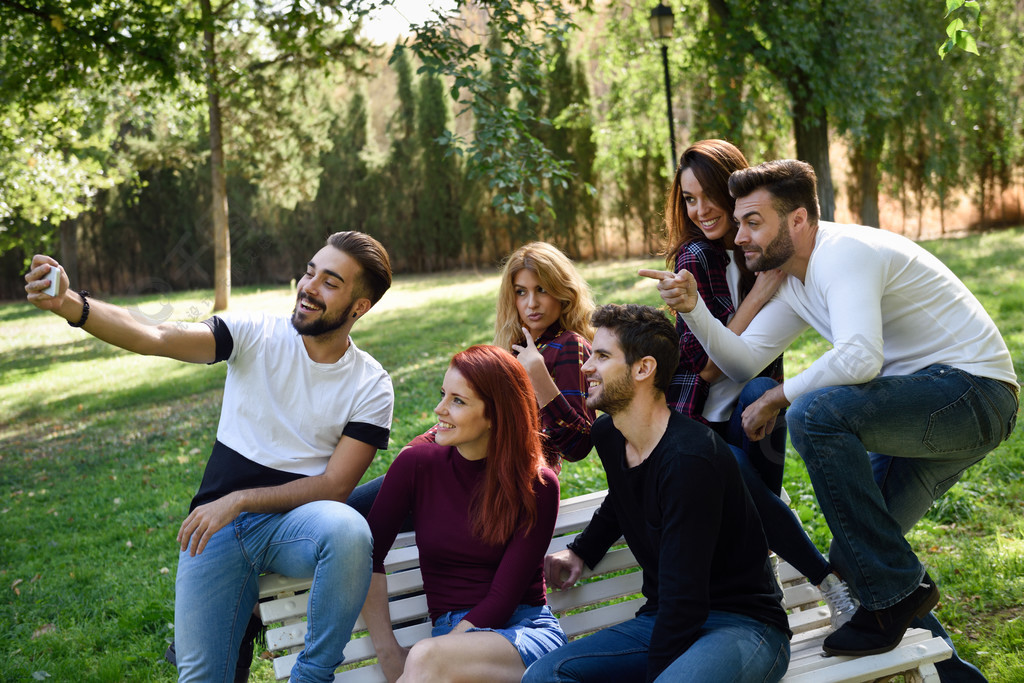 采取selfie的小组朋友在都市公园五个年轻人穿着便服