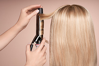 美发师用卷发器卷曲长发长直发的美丽女人流畅的发型