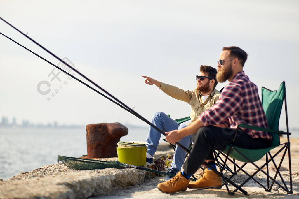 休闲和人们观念-快乐的朋友，与钓鱼竿在海上码头钓鱼竿在
