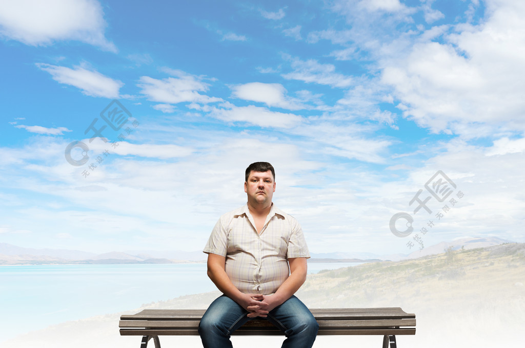 胖子胖男人坐在长椅上看着相机