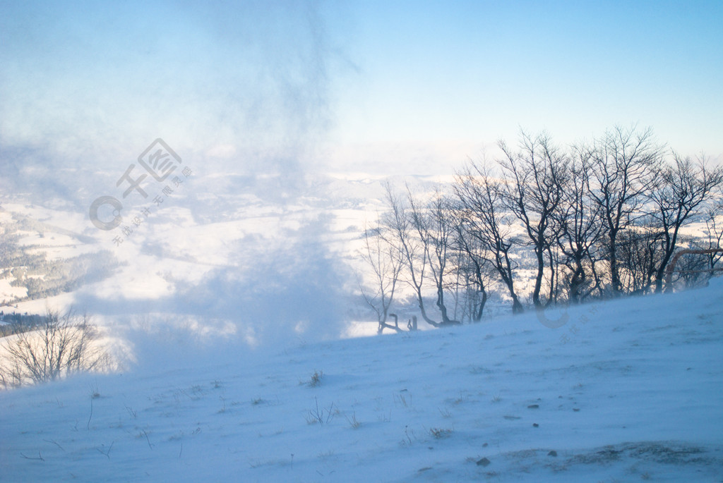 风吹雪覆盖的山峰和远处的一座木房子山中的雪风