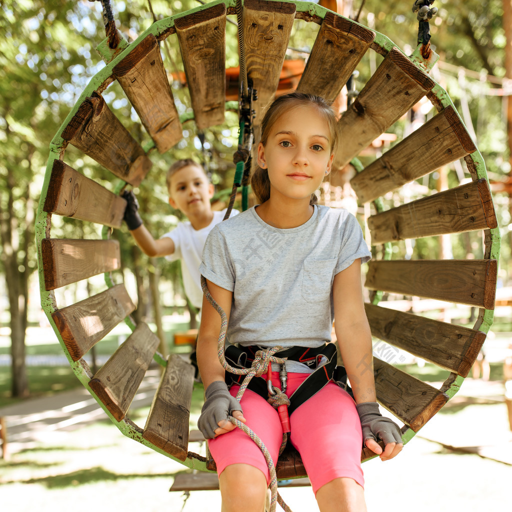 在设备的微笑的孩子在绳索公园,操场上升孩子们爬上吊桥,度假,危险