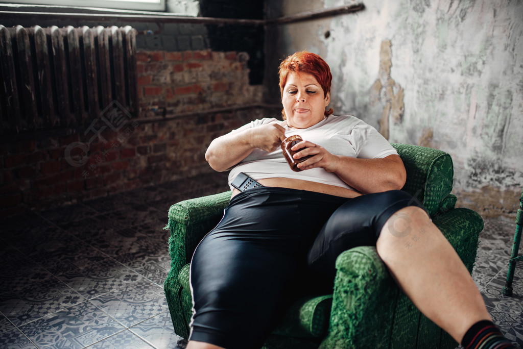超重的女人坐在椅子上吃糖果不健康的生活方式肥胖