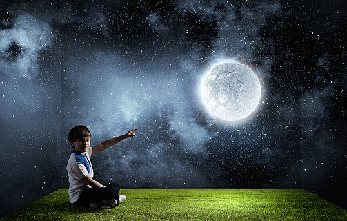 男孩探索世界可爱的男生坐在地板上,用手指抚摸月亮