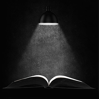 在黑暗中的老书已打开的书,在黑色背景上的页面上有光