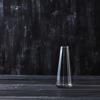 牛奶<i>保</i>存的空的玻璃容器在与地方的黑背景您的文本的透明玻璃花瓶空在一张黑木桌，背景上