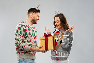 人和假日概念-愉快的加上<i>画</i>象在丑陋的毛线衣<i>党</i>的圣诞节礼物幸福的夫妇，在圣诞毛衣和礼品盒