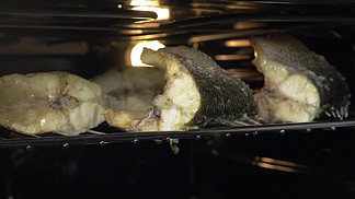 鱼特写镜头射击编结烹调在热的烤箱有人正在打开烤箱门并检查是否完成