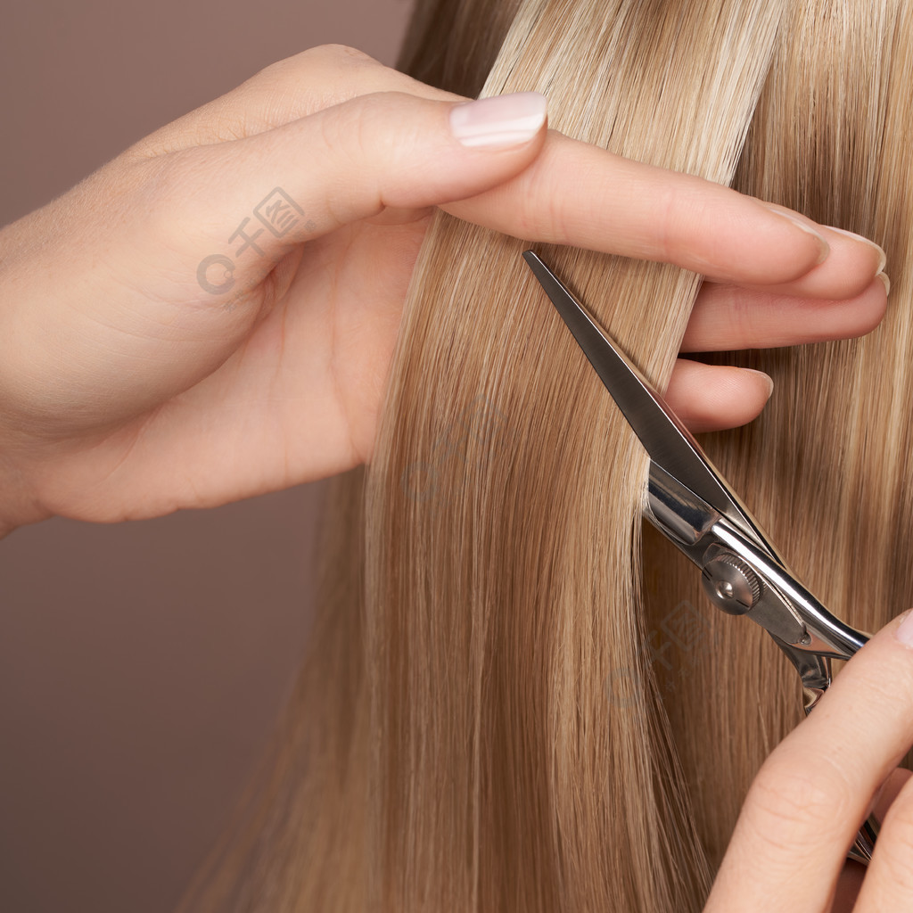 师用剪刀剪长长的金发美发沙龙发型师护理和美容美发产品染过的头发
