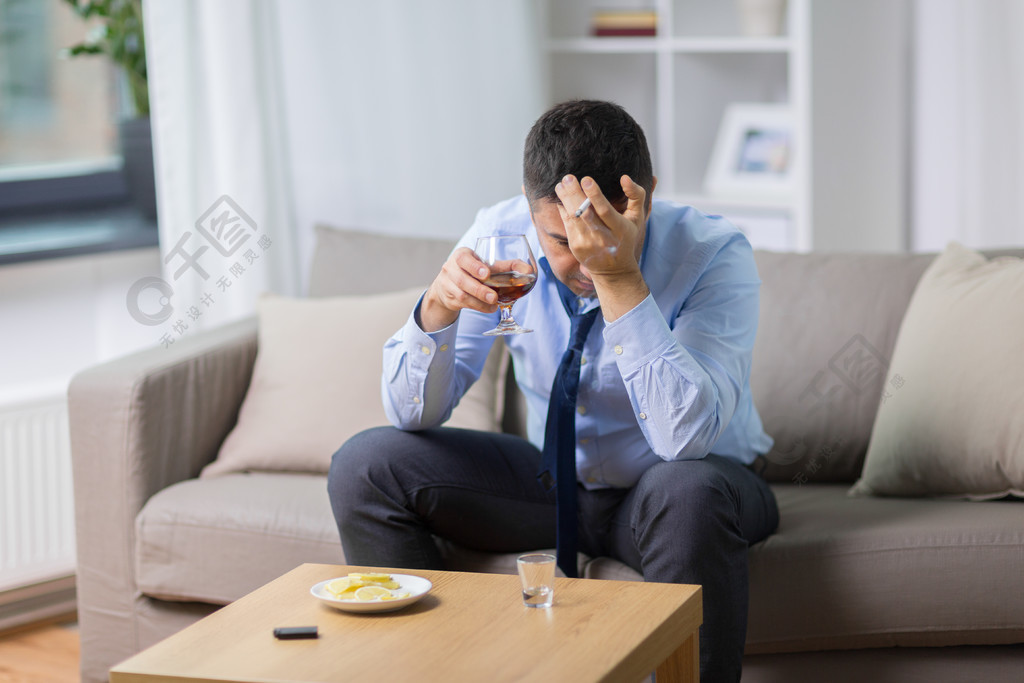 觀念-男性酒精飲用的白蘭地酒和抽菸的香菸在家醉酒的男人喝酒,抽菸