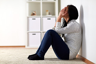 人,悲伤和家庭暴力的概念— —不快乐的女人,坐在地板上,在家里哭不