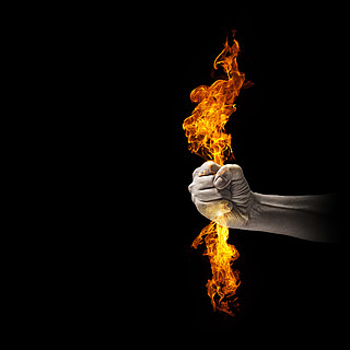 手中有火人类的手,握着火火焰的特写