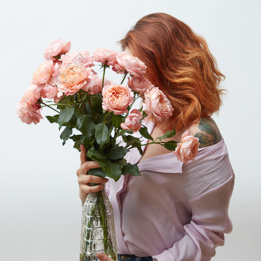 有拿着大花束桃红色玫瑰在一个玻璃花瓶的纹身花刺的一名妇女在与拷贝