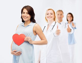怀孕，<i>医</i>疗保健，<i>医</i>学，人们和期望的概念— —幸福的孕妇，与红色的心形触摸她的肚子，在显示大拇指背景组的<i>医</i><i>生</i>或产科<i>医</i><i>生</i>