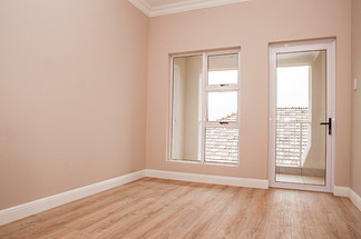 新建房屋的空卧室，地板铺有层<i>压</i>地板，玻璃门窗通向露台