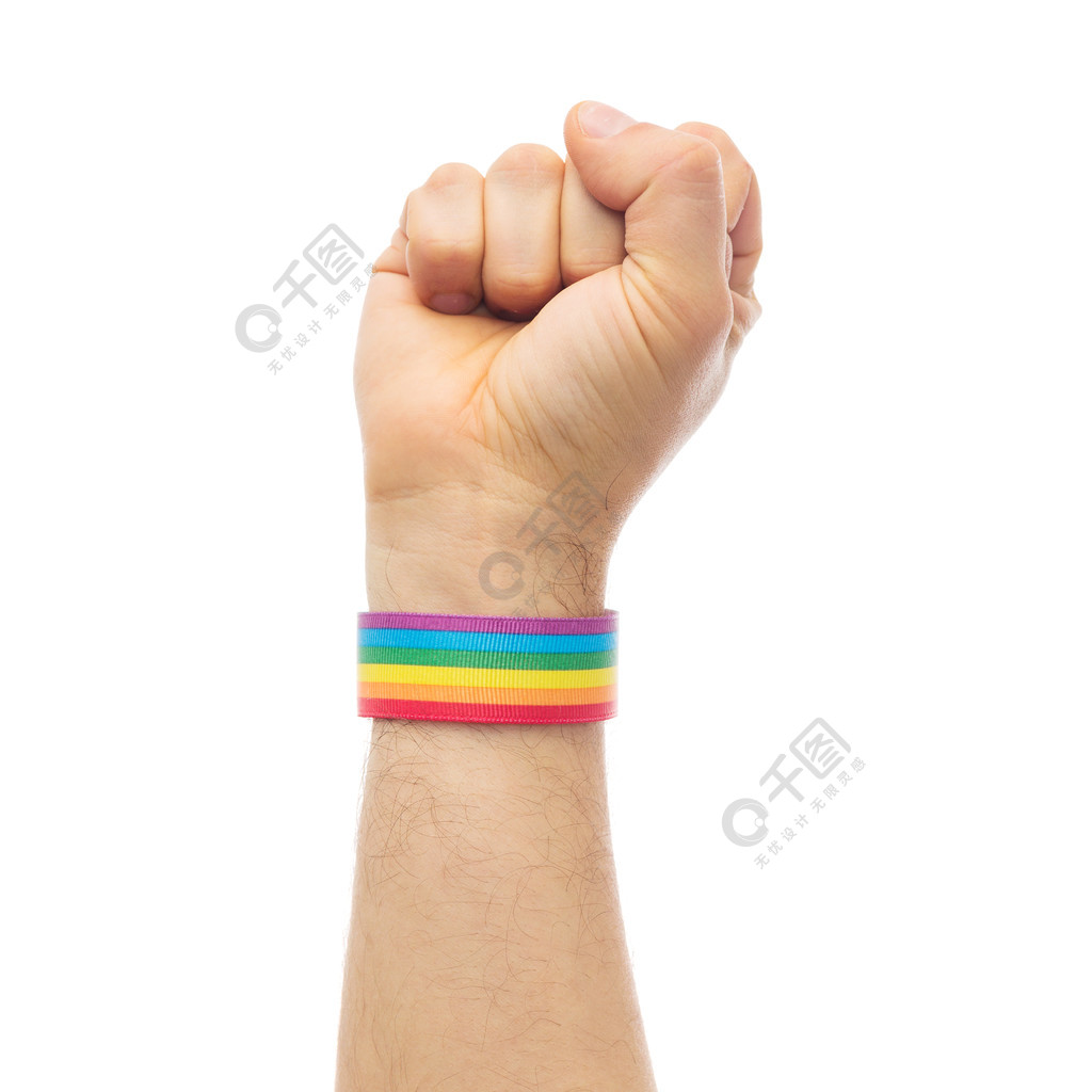 lgbt，同性关系和同性恋概念-接近显示拳头的男性手佩带的同性恋自豪日知名度袖口与同性恋骄傲彩虹腕带的手显示拳头同性恋骄傲彩虹腕带的手显示拳头