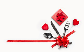 与利器的欢乐桌餐位餐具和红色弓和丝带，礼物盒和心脏在白色背景，横幅情人节晚餐邀请或周年纪念日，宴会，庆典的布局