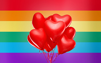 聚会，情人节和<i>lgbt</i>概念-红色氦心形气球在彩虹旗背景红色心形氦气球在彩虹旗