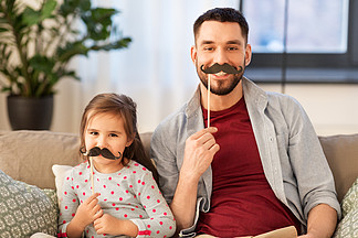 家庭，童年和父亲的概念— —快乐的父亲和小女儿留着胡<i>须</i>聚会道具在家玩乐父亲和女儿在一起开心的小胡子