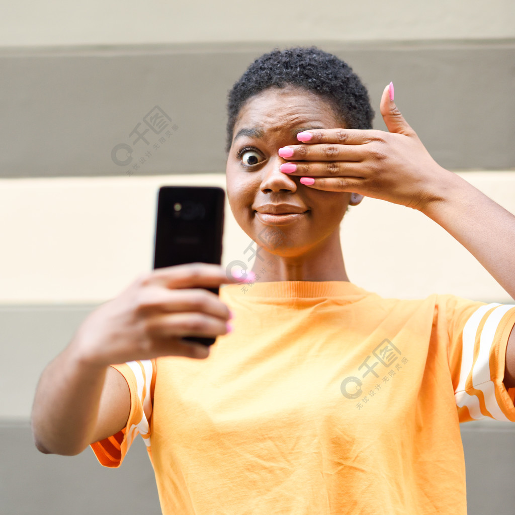 穿着便服的女孩有趣的黑人女性,自拍照拍照与快乐的表情在户外