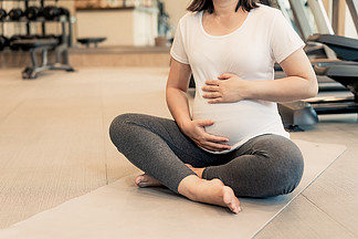 活跃孕妇锻炼在瑜伽室的健身中心年轻怀孕的母亲抱着婴儿的肚子里产<i>前</i>产<i>前</i>保健和妇女怀孕的概念