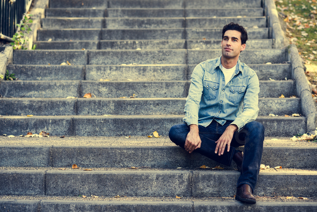 一个年轻英俊的男人的肖像,时装模特,坐在城市楼梯上的正式发型,穿着