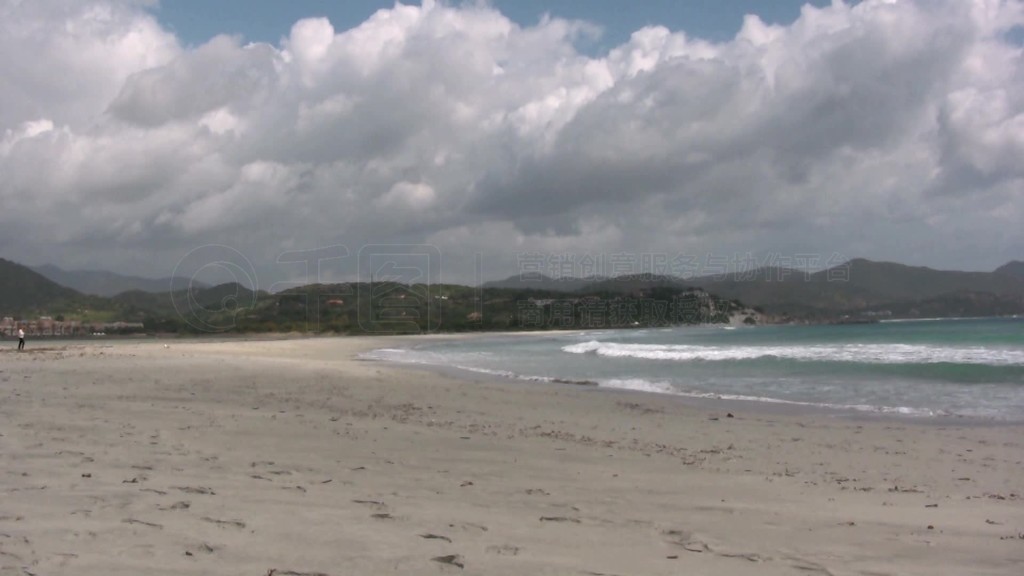 Blick auf einen Strand mit Dnnen im Hintergrund mit Wolken