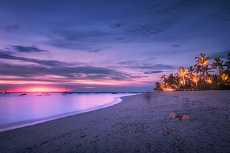 沙滩与夕阳多彩夏天棕榈树热带景观<i>海</i>边，模糊水，棕榈树，船和游艇，<i>海</i><i>洋</i>，紫色的天空有云夜晚在异国情调的非洲旅行