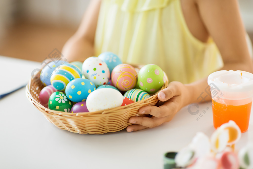 复活节，假日和人概念-接近女孩用在柳条筐的色的鸡蛋在柳条篮子里的复活节彩蛋的女孩特写