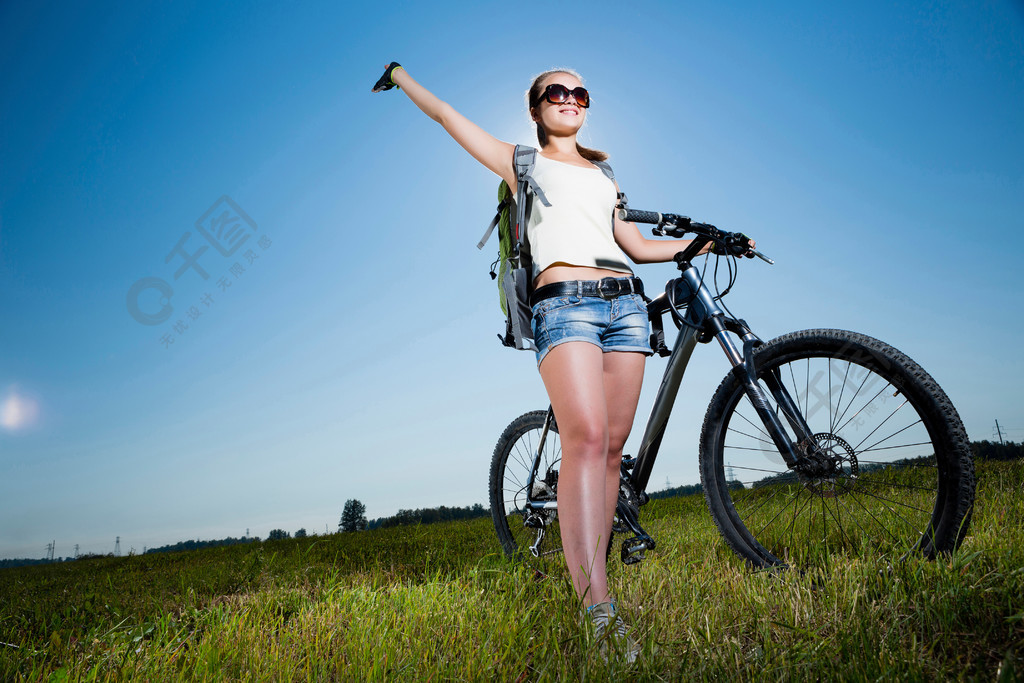 您積極的生活方式年輕的運動型女孩與揹包騎自行車沿路邊