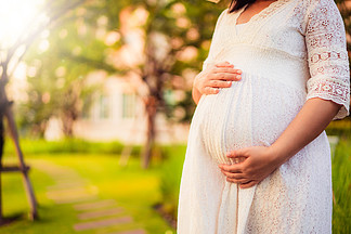 感到的孕妇满意对新的生活在庭院家，当照顾她的孩子时年轻怀孕的母亲抱着婴儿的肚子里产<i>前</i>产<i>前</i>保健和妇女怀孕的概念