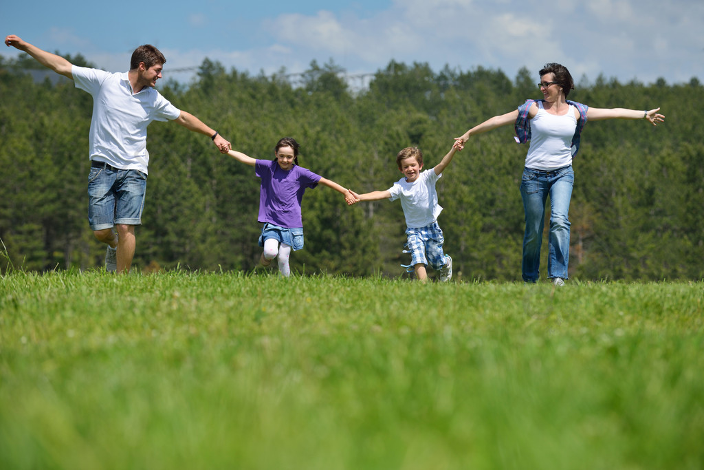 幸福的年轻家庭,与他们的孩子们玩得开心,在大自然中户外放松与背景中
