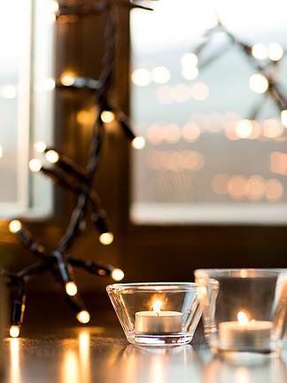 hygge，装饰和圣诞节概念-在家<i>燃</i><i>烧</i>在灯笼和欢乐诗歌选的蜡烛在窗台用花环灯在窗台上<i>燃</i><i>烧</i>的蜡烛