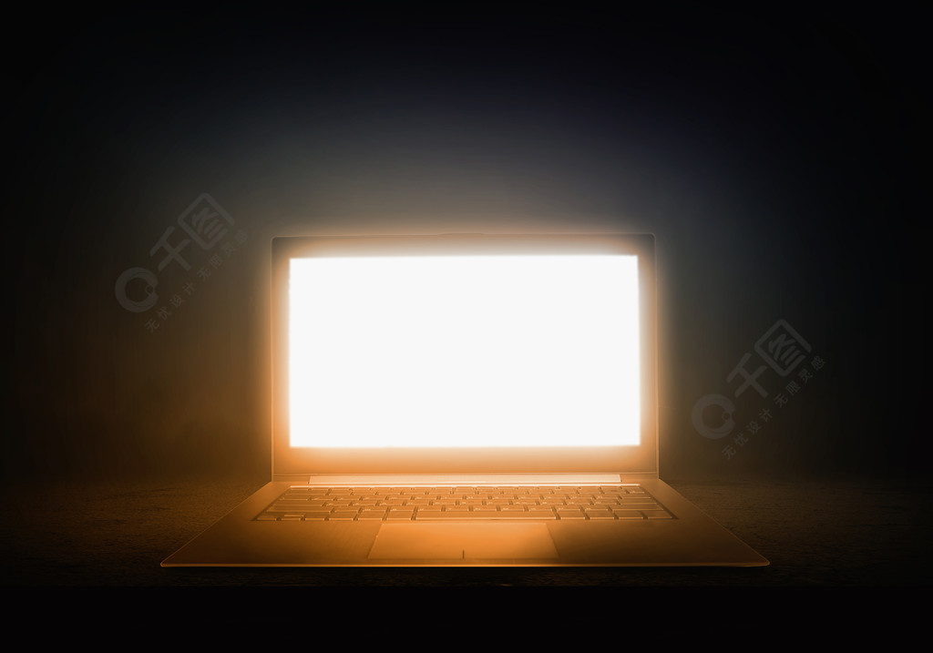 发光的笔记本电脑用来自屏幕在深色背景上的光打开笔记本电脑