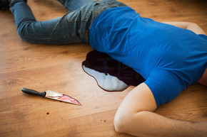 谋杀，杀戮和人们观念-死者的尸体和刀子躺在犯罪现场的地板上的血液（舞台照片）犯罪现场的地板上躺着的死人尸体