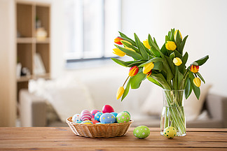 <i>复</i>活节，假日，传统和对象概念-在篮子和郁金香的色的鸡蛋在家开花篮子和花朵在家中的彩色的<i>复</i>活节彩蛋