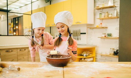 孩子廚師做麵糰,孩子準備蛋糕小女孩戴著帽子做飯,在碗里加黃油