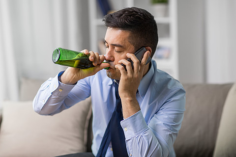 酒精成癮和人們觀念-男性酒精飲用的啤酒和在家拜訪智能手機男人喝酒