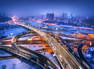 路的鸟瞰图在现代城市在雾的晚上交通顶视图在高速公路的与高架路，汽车，大<i>厦</i>，照明的冬天都市风景欧洲的立交桥高速公路